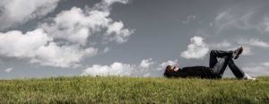 man laying on the grass looking at clouds