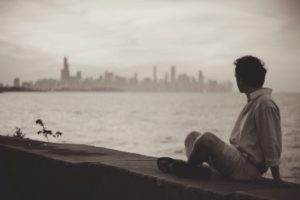 man sitting by himself looking at the city skyline