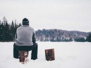 man sitting on a stump in the snow