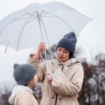 mom standing in rain holding umbrella over child