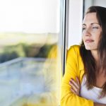 woman standing by window looking out